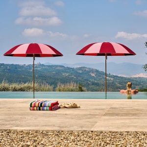 Zwei rot-Rosé gestreifte Sonnenschirme an einem Swimmingpool