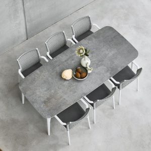 Ein rechteckiger Tisch mit einer graumelierten Keramikplatte und sechs Stühlen. Auf dem Tisch ein wenig Dekoration